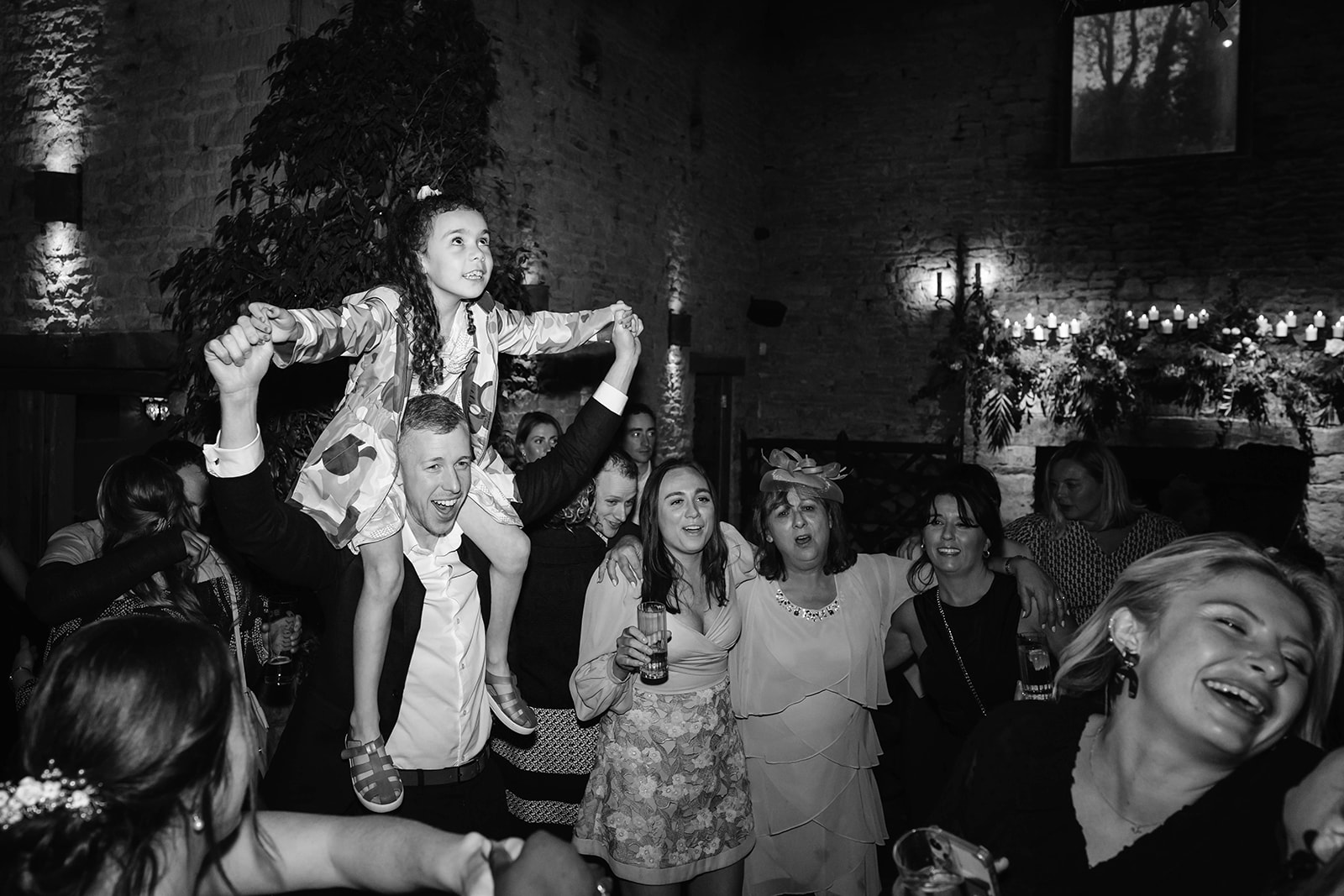 black and white of guests dancing with child on shoulders
