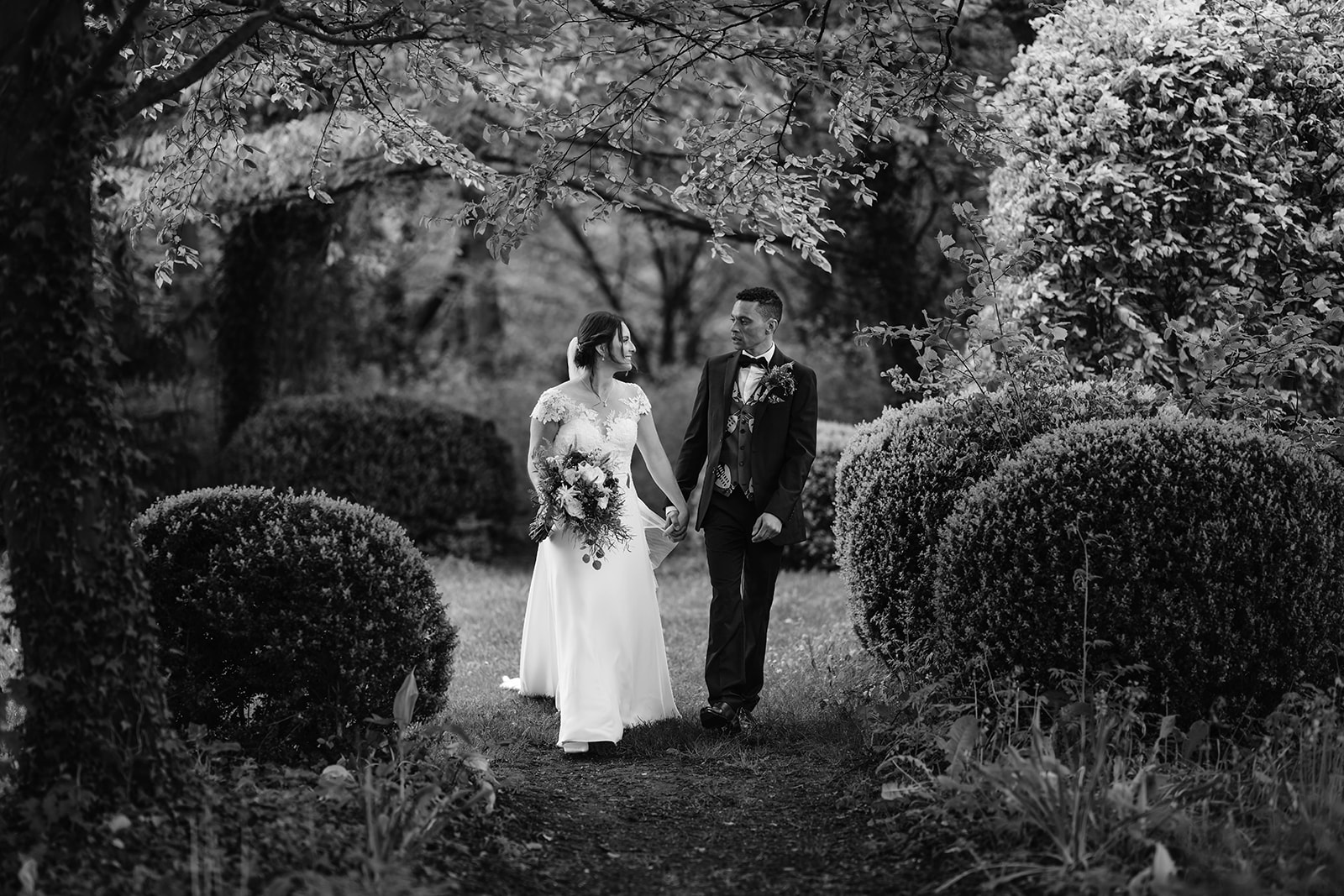 Black and White photo of bride and groom in trees and shrubs