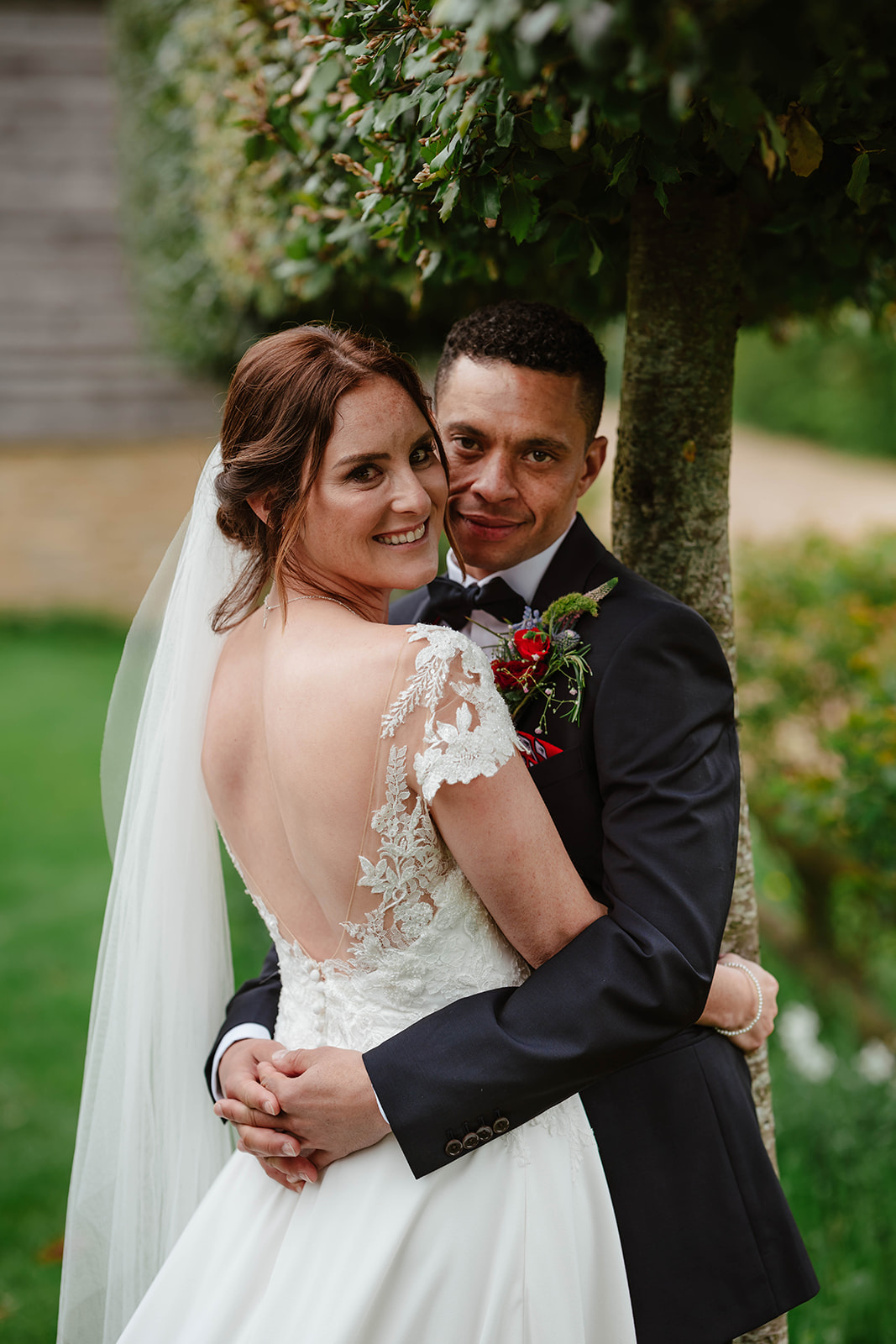 Bride and Groom embracing next to trees