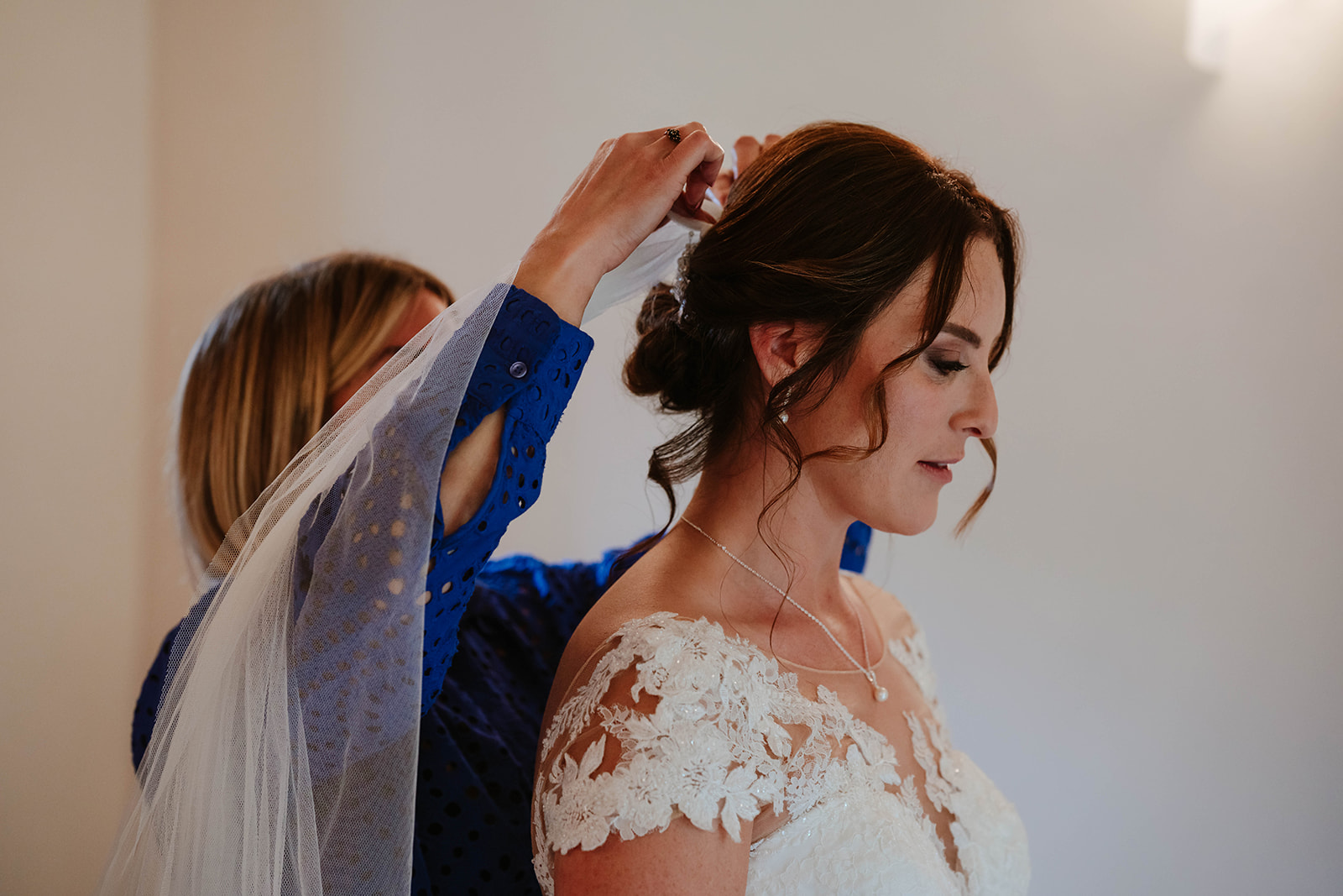 Bride having her veil attached by hairdresser