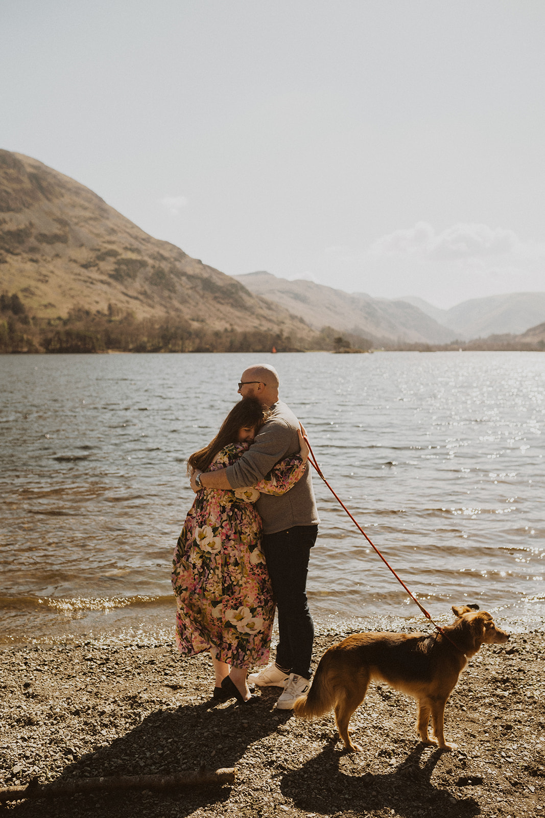 Mum and Dad embrace by a lake on maternity photoshoot
