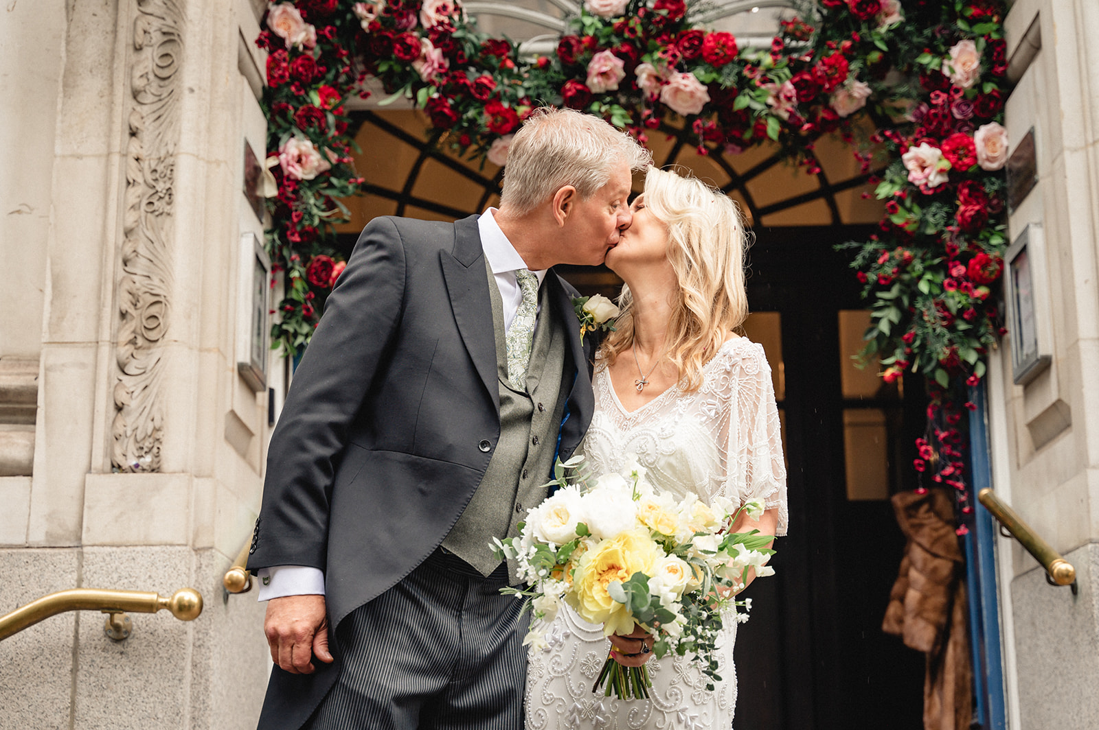 Portrait of Lindsay and David shares kiss on the steps of Chelsea Town Hall