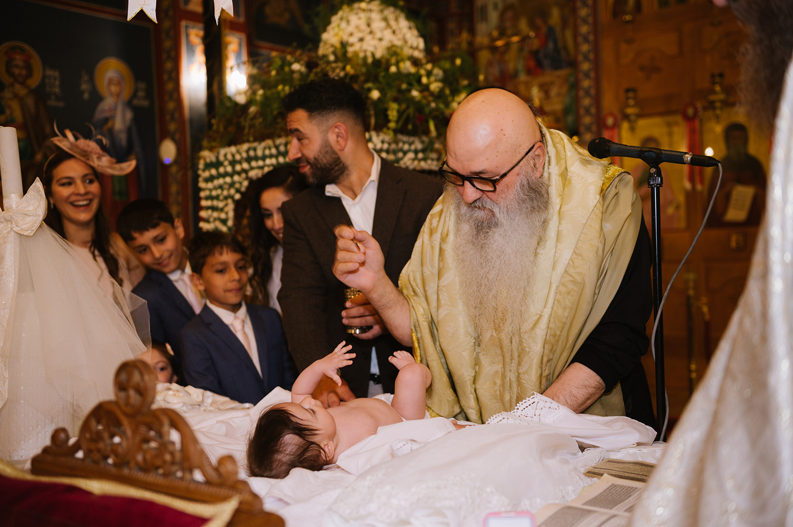 greek orthodox priest anointing the baby with oil at her christening