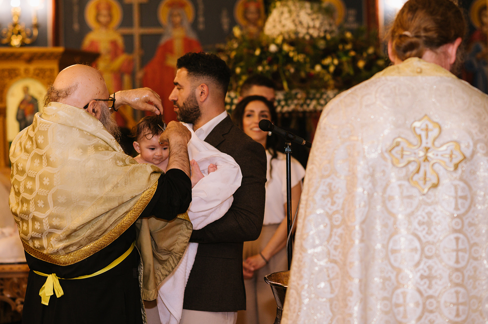 greek orthodox priest cutting the baby's hair at her christening