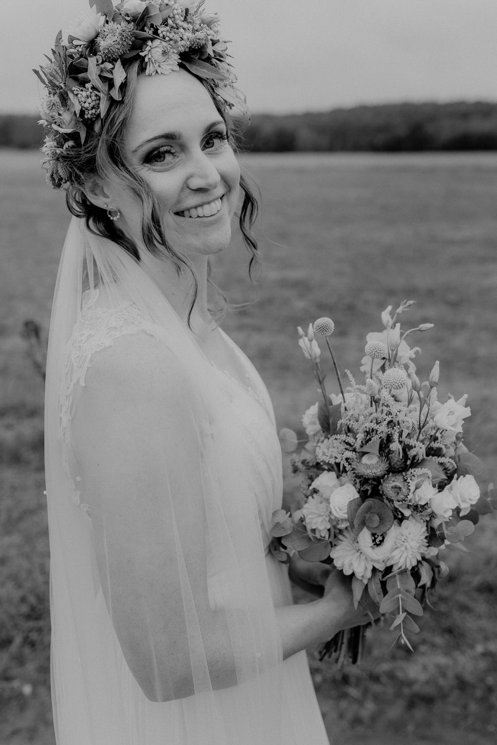 lachende Braut mit Wedding Bouquet und Flowercrown als modernes Schwarzweiß Foto