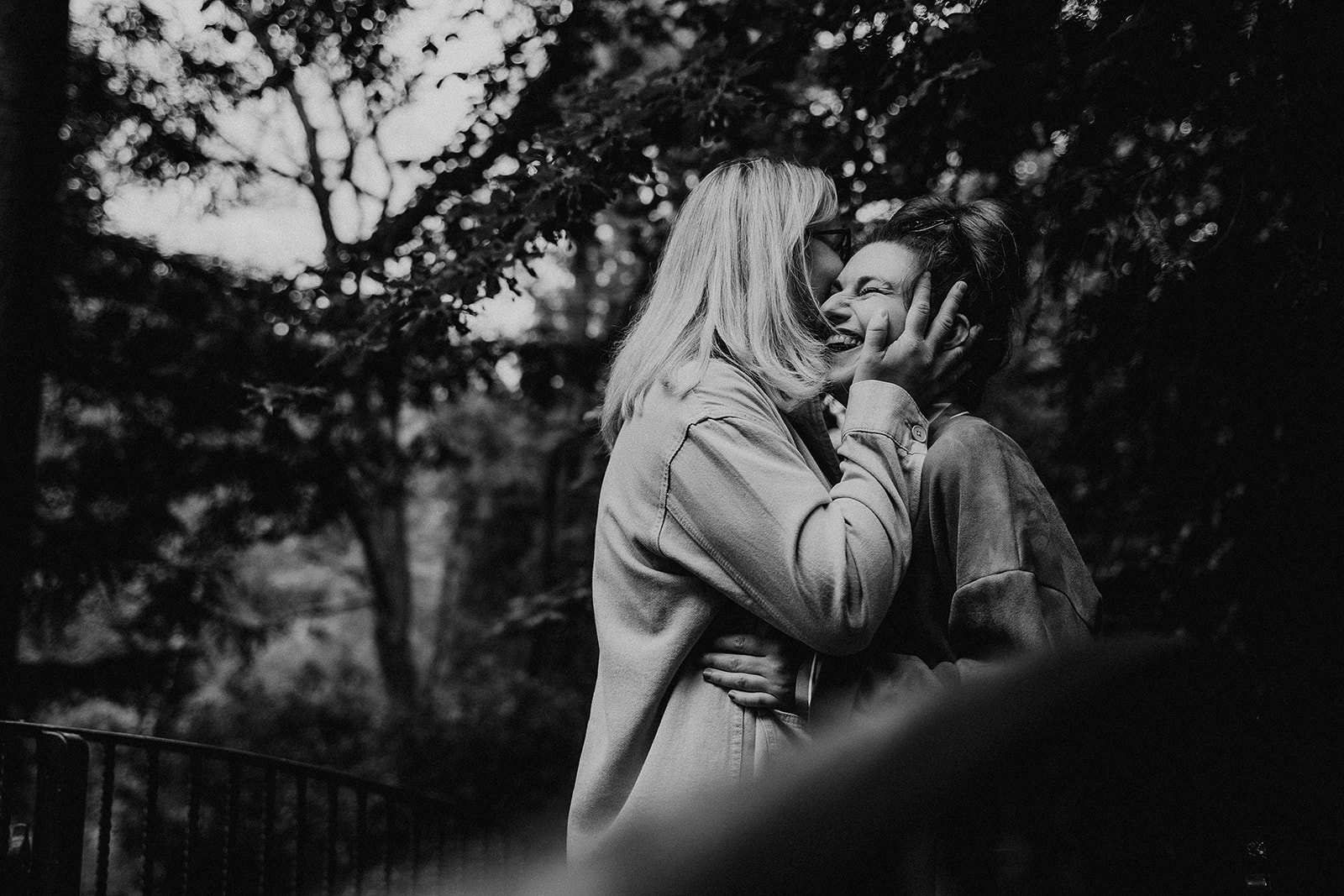 couple cuddle on a bridge in a Southampton park - couples photography in black and white
