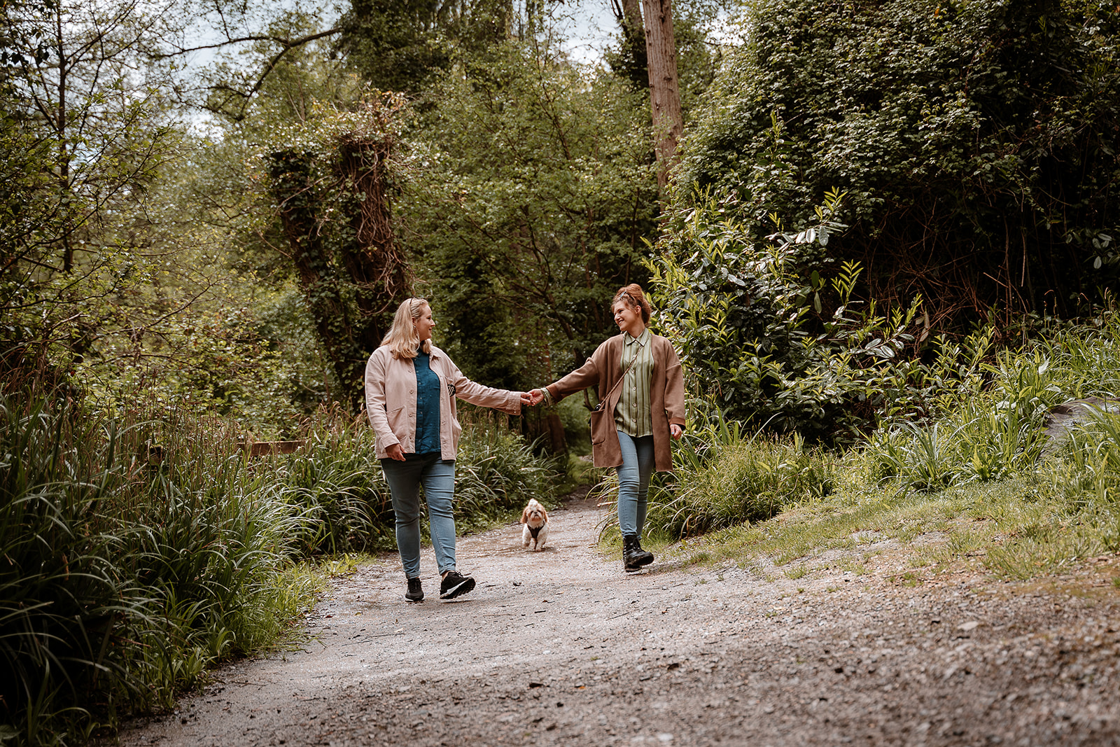 couple walk hand in hand together along a woodland path - couples photography Southampton 