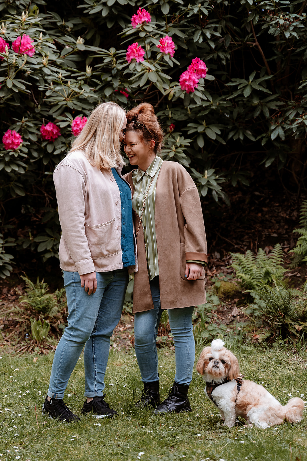 same-sex couple pose in front of pink flowers with their Shih-Tzu