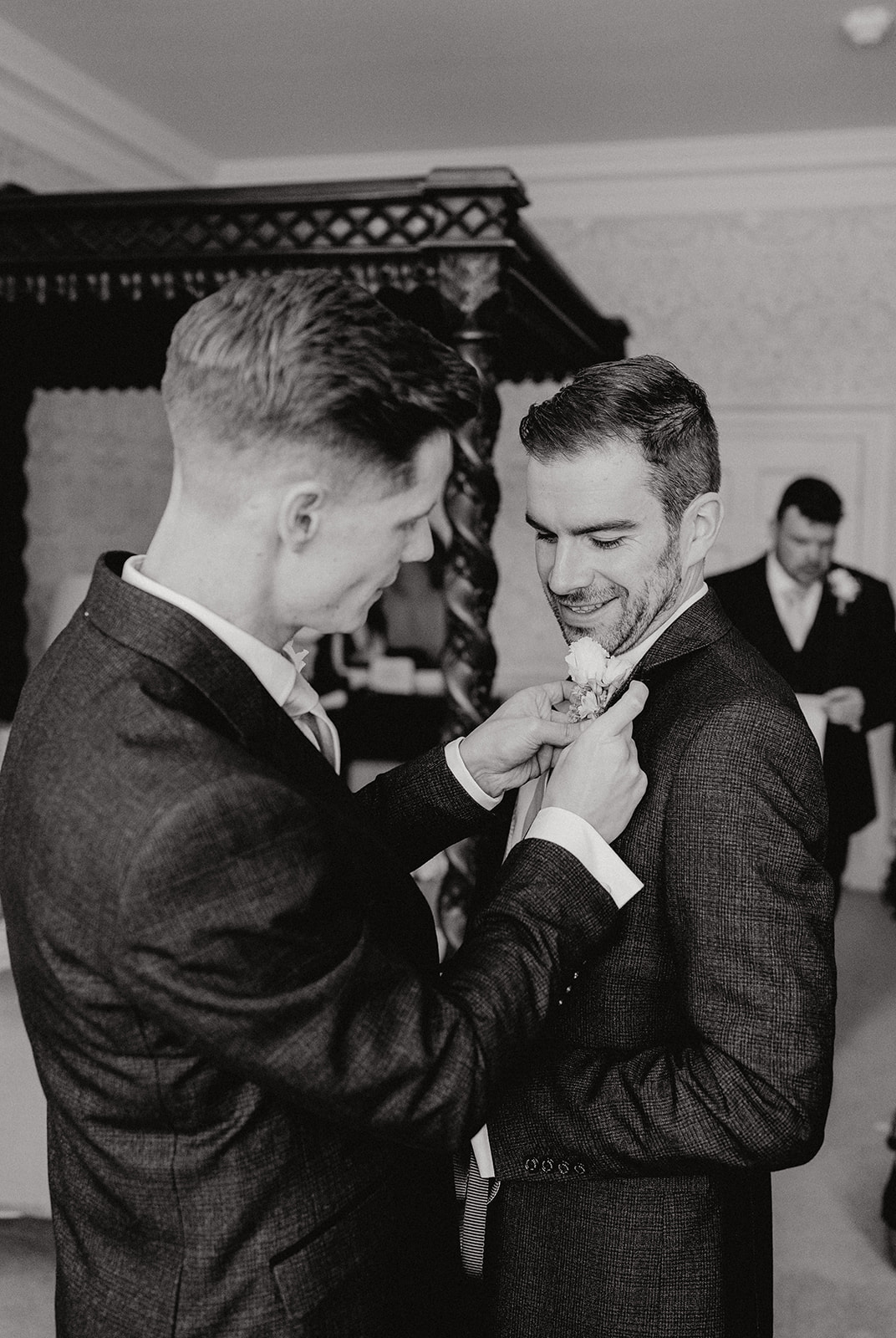 Groom having his button hole put on by best man