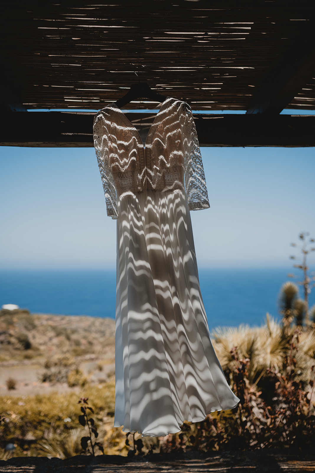 Abito della sposa all'ombra di un Dammuso tipico di Pantelleria