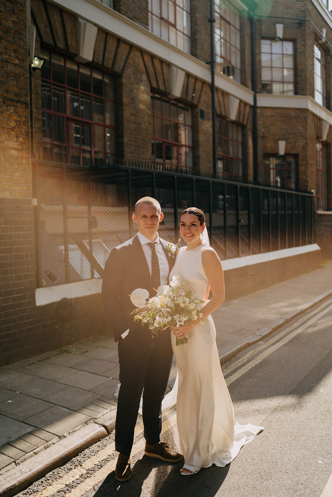 creative sunflare wedding portrait in Shoreditch ith bride and groom relaxed in front of the camera