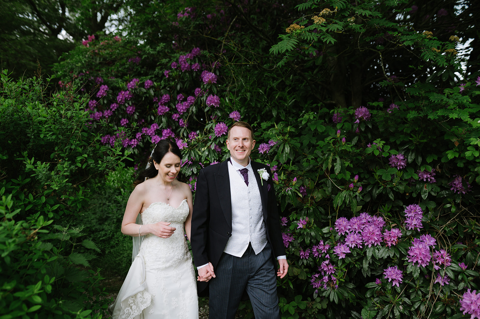 bride and groom walking past flowers in a relaxed wedding photo