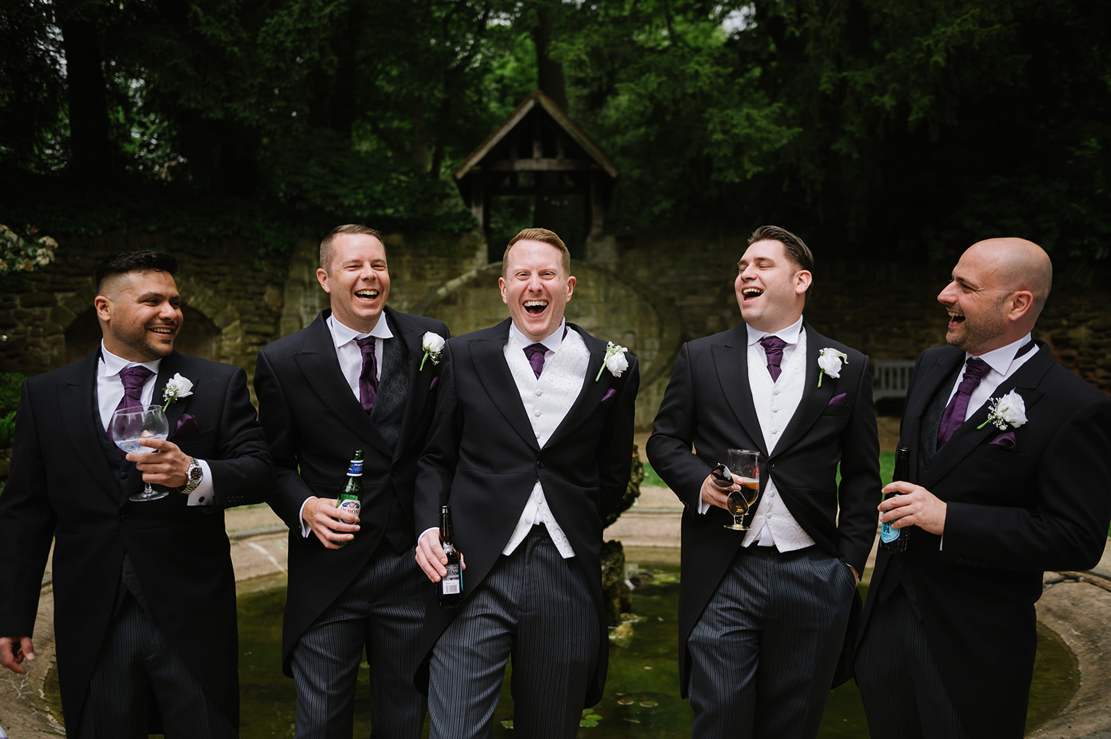 groom and groomsmen in matching suits laughing together before the wedding ceremony