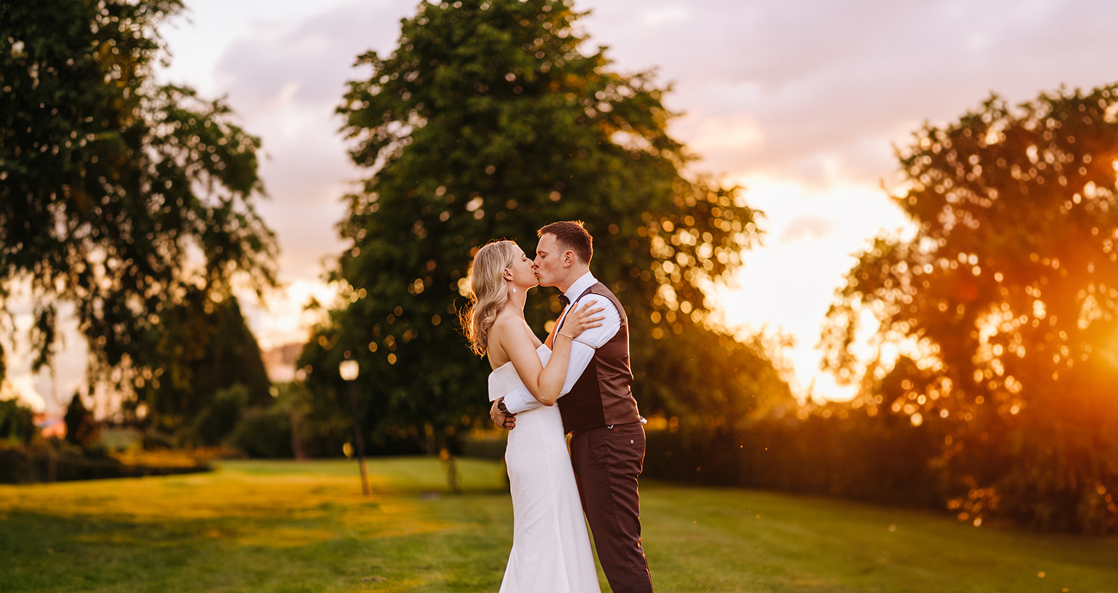 Bride and groom kiss in castle durrow grounds with sunset behind them
