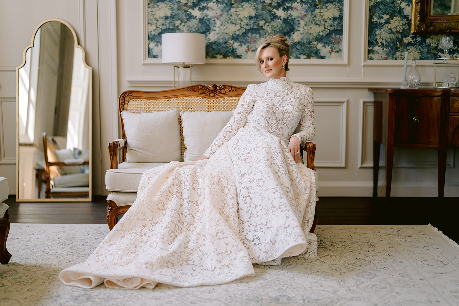 bridal portrait of bride sat on a chair in the brympton house wedding suite. bride in lace dany tabet dress sleeves 