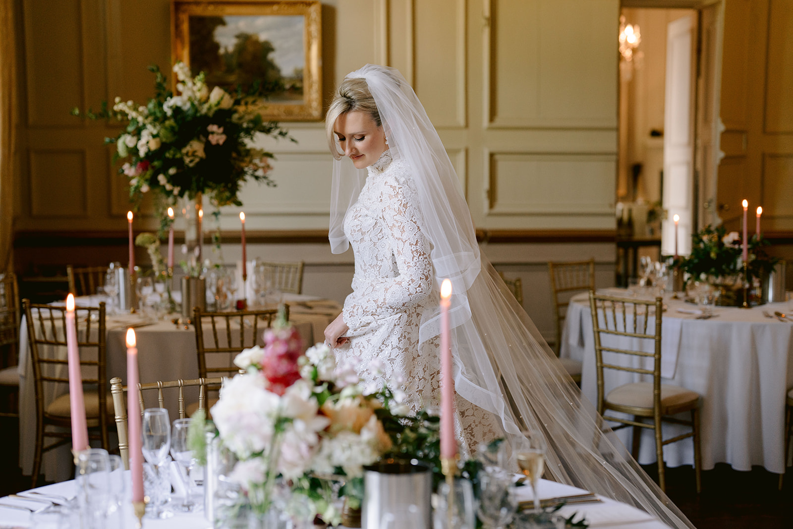 bride looking at the wedding breafast decor in her brympton house wedding wearing a lace dress