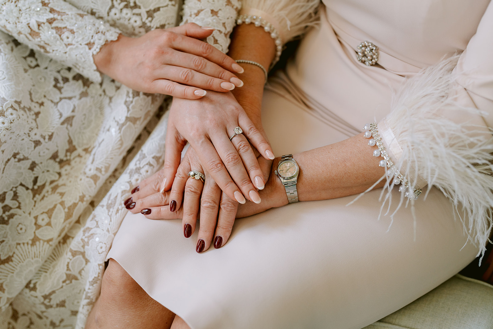bride and mothers hands on top of each other showing the wedding rings
