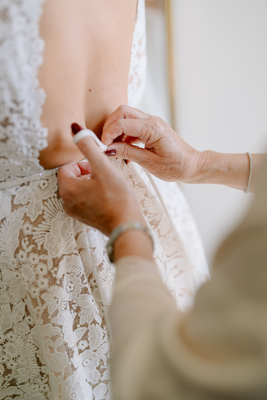 brides mum fastening her lace wedding dress buttons