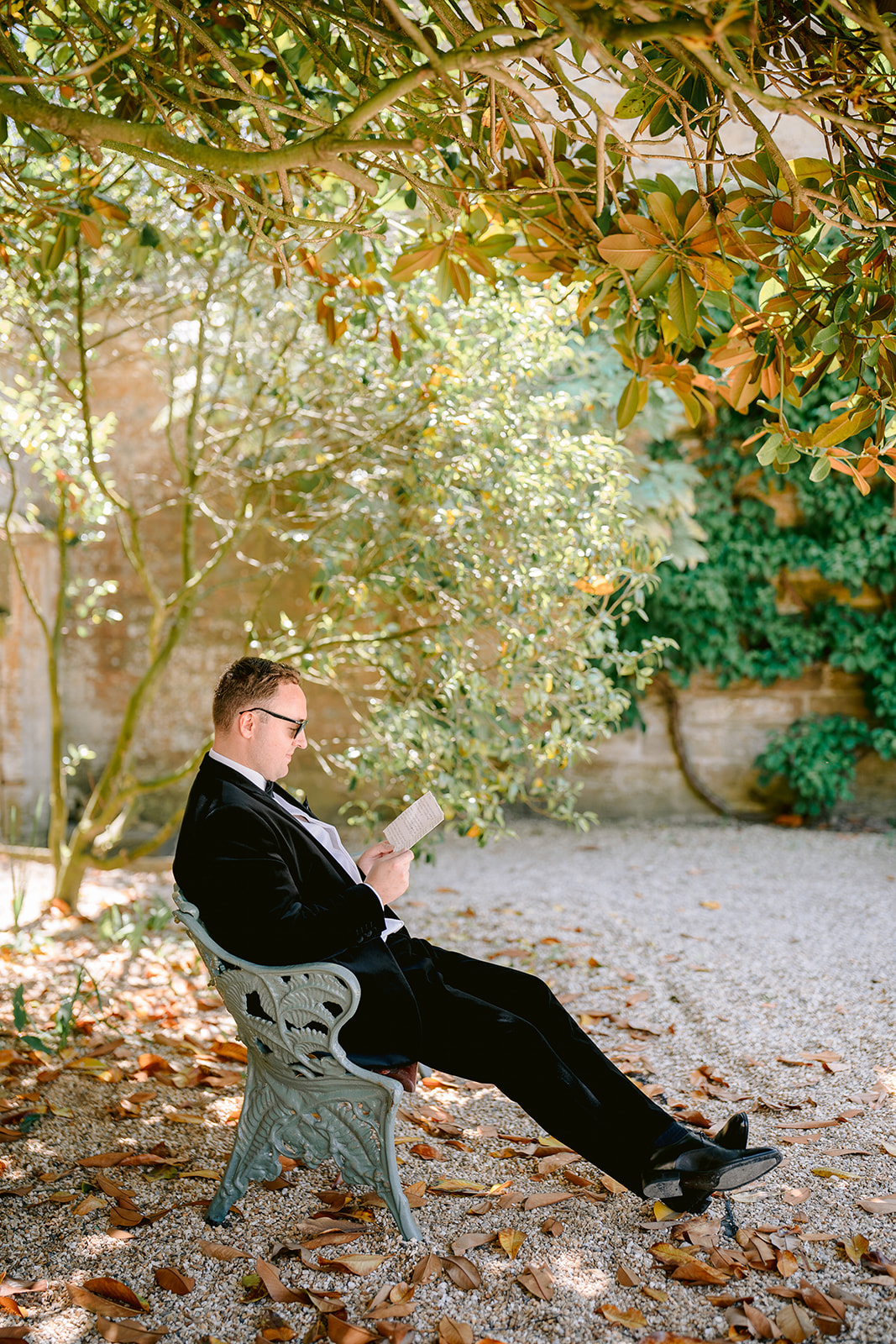 groom reading card under the tree sat on bench