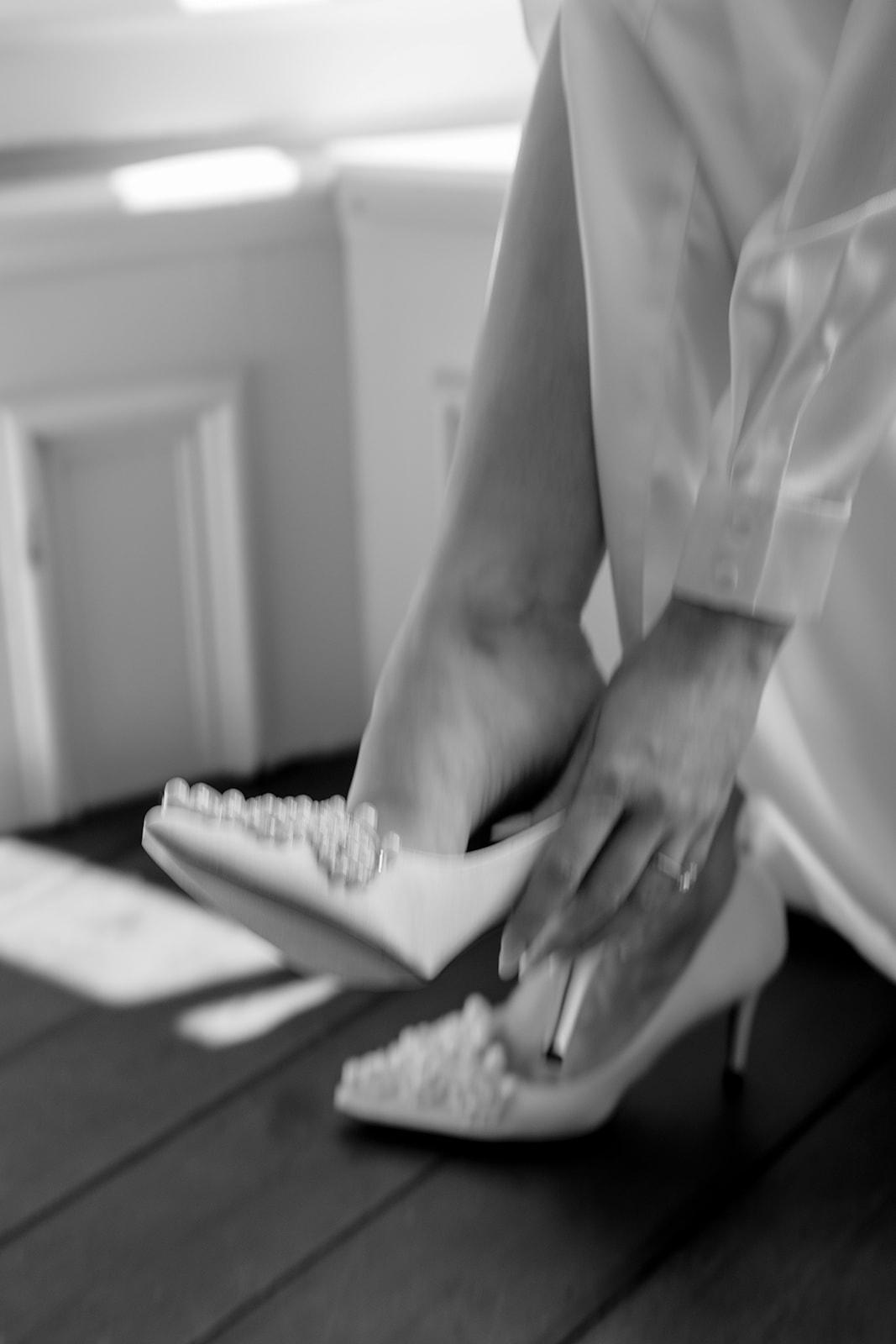 long exposure blurry photo in black and white of bride putting shoes on