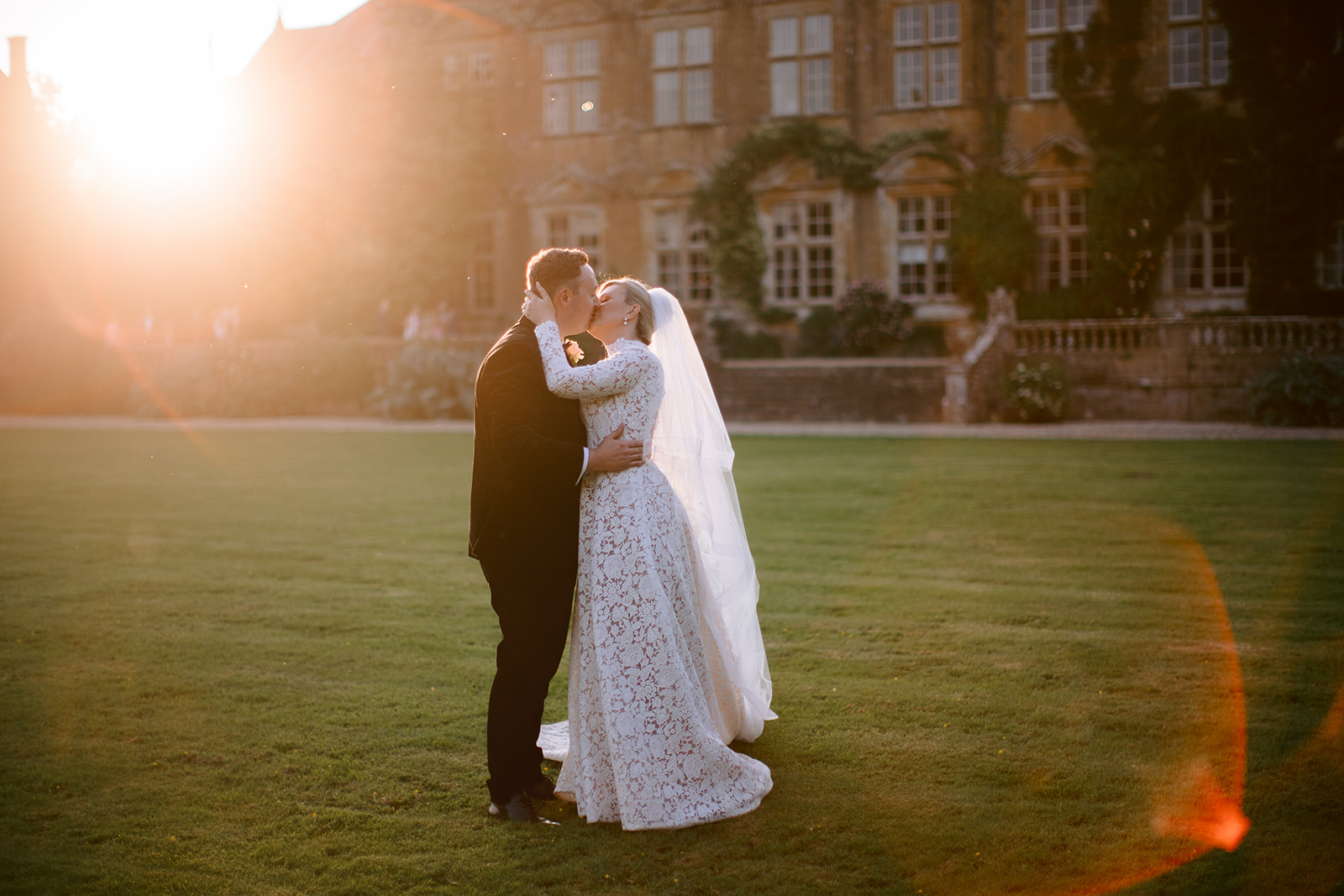 sun flare coming into the photo as the bride and groom kiss at their brympton house wedding