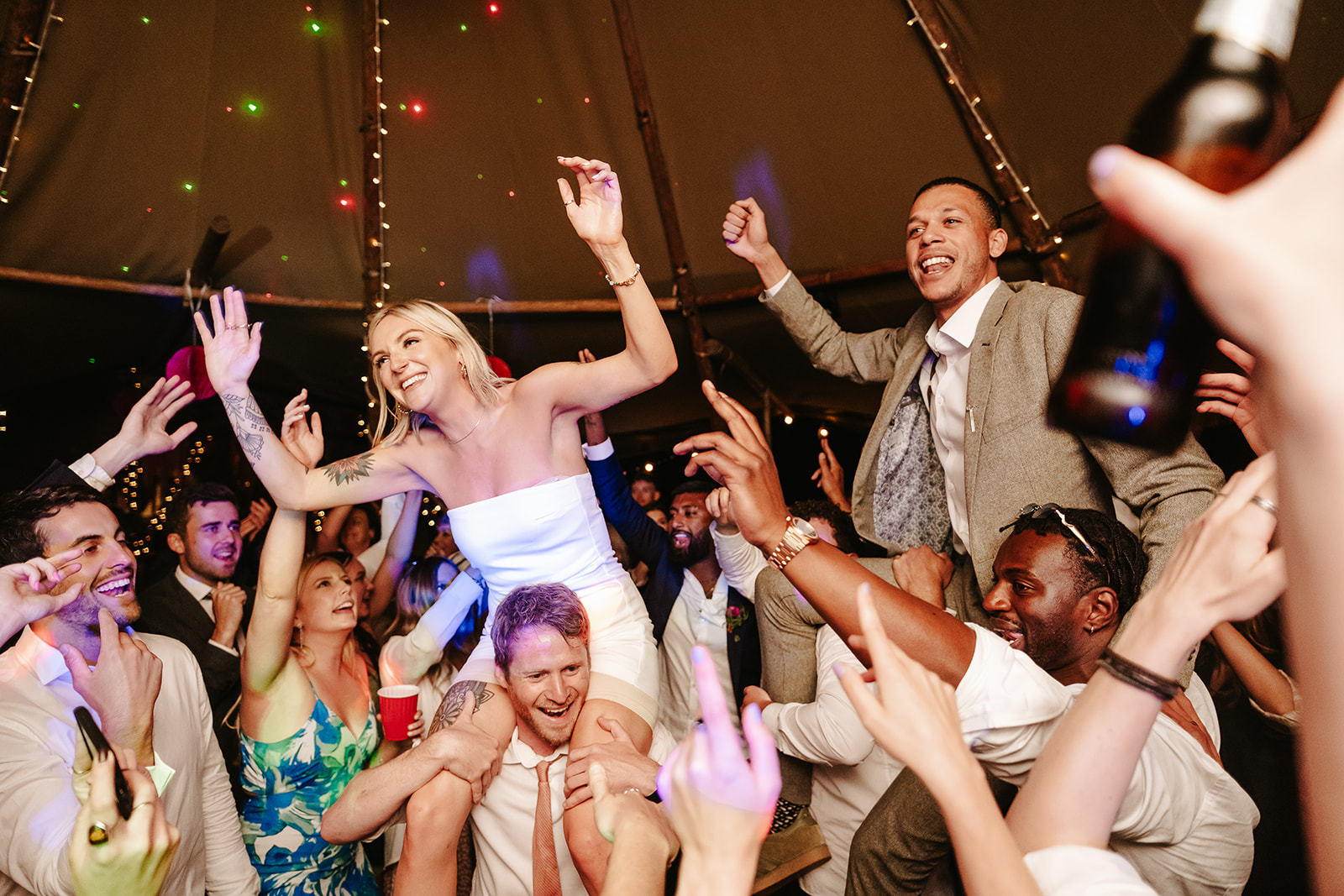 A couple dancing on the shoulders of guests during the wedding reception