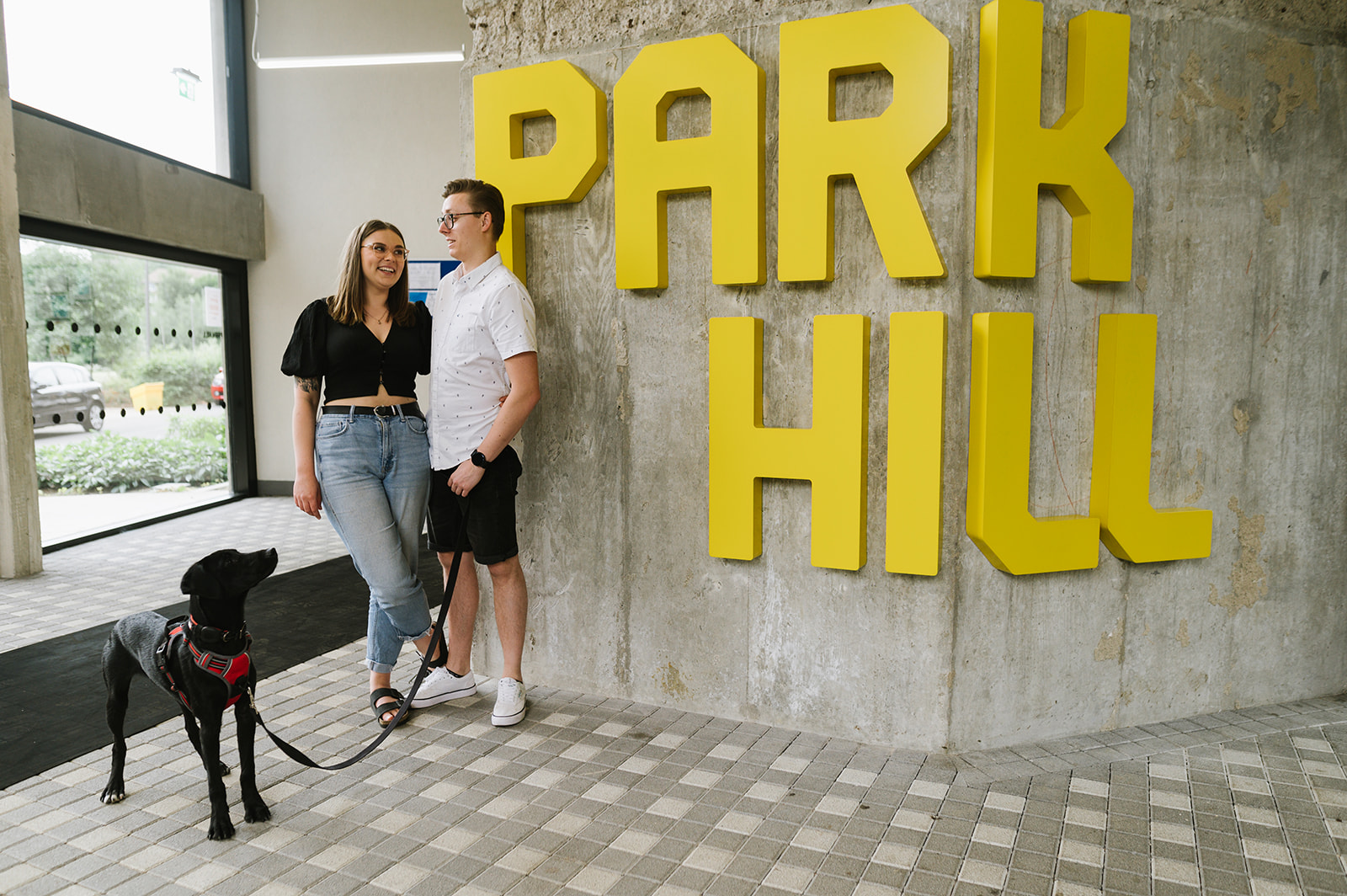 Couple and their dog with the Park Hill sign for their engagement photos