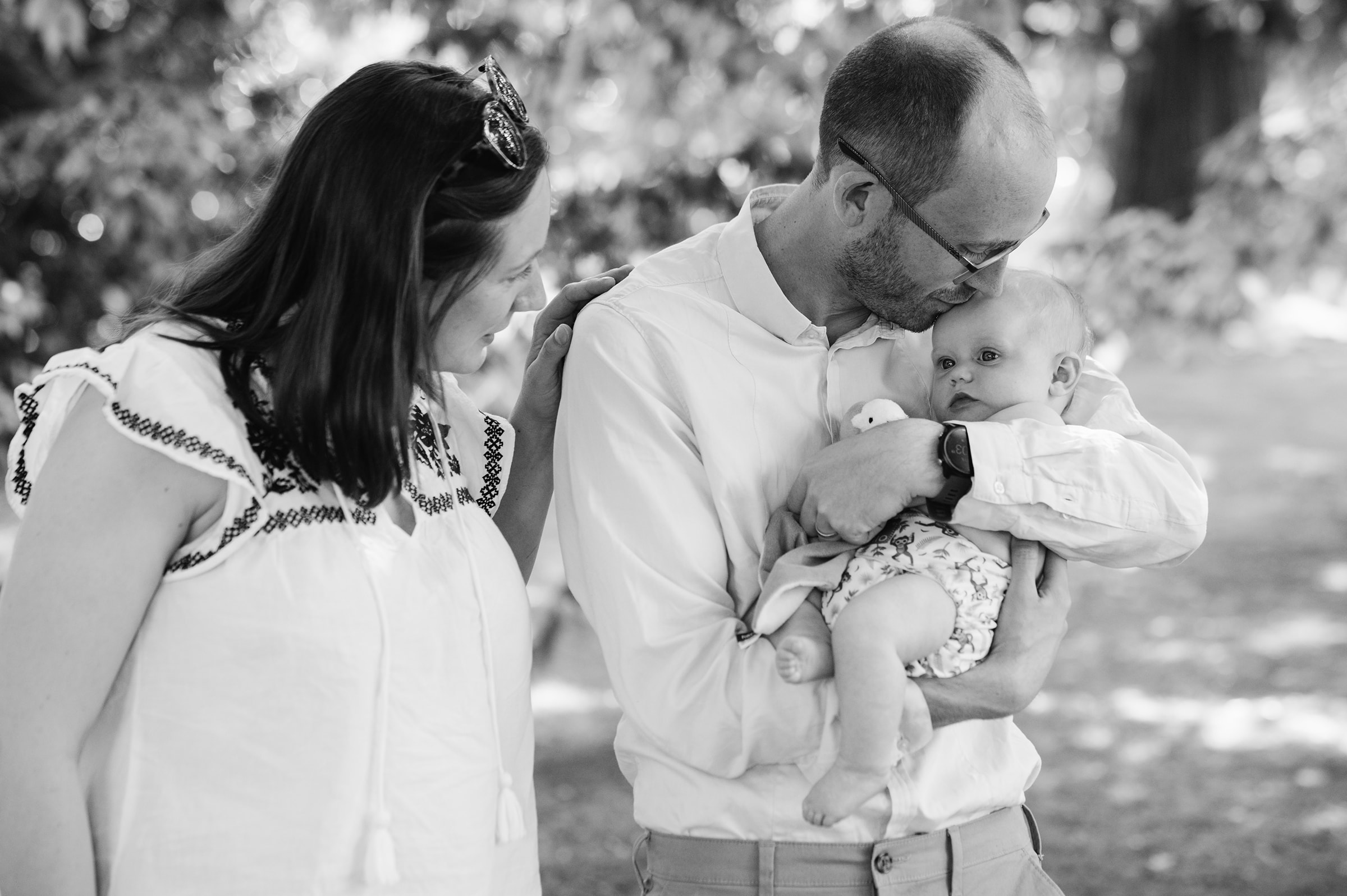 Couple cuddle their baby daughter in Sheffield Botanical Gardens for some relaxed family photos
