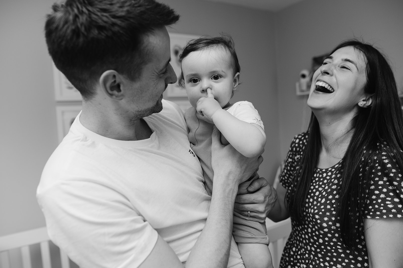 relaxed family photo of parents holding baby boy and laughing 