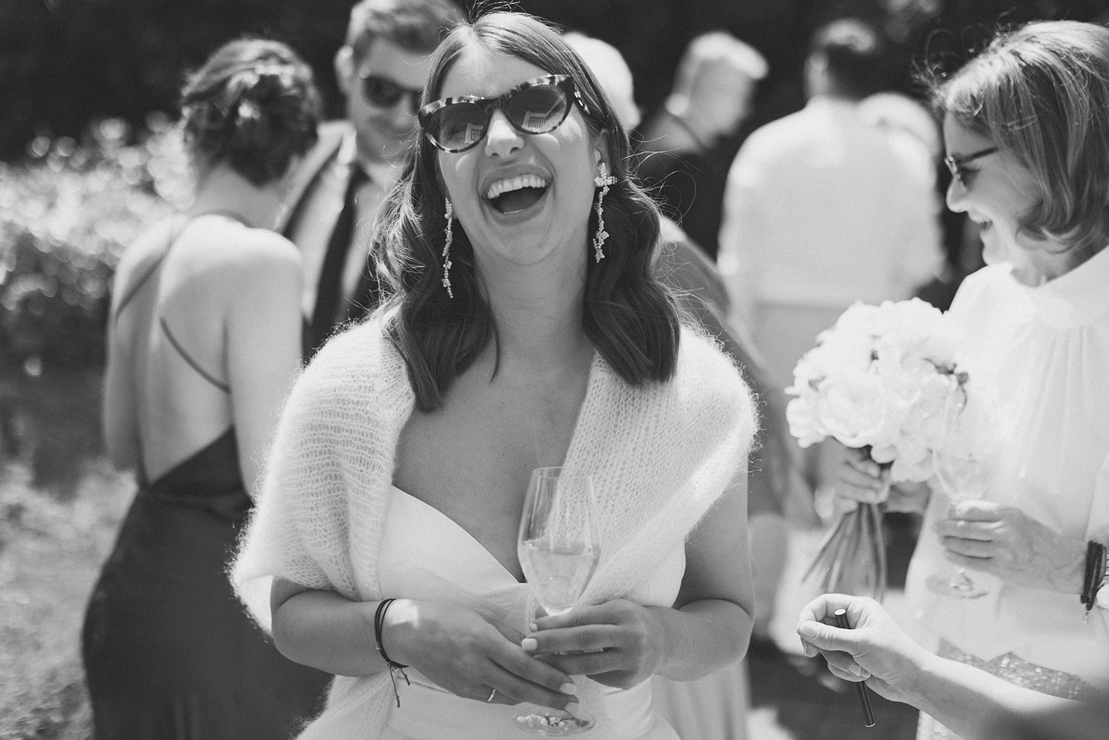 Braut mit Sonnenbrille lacht herzhaft 