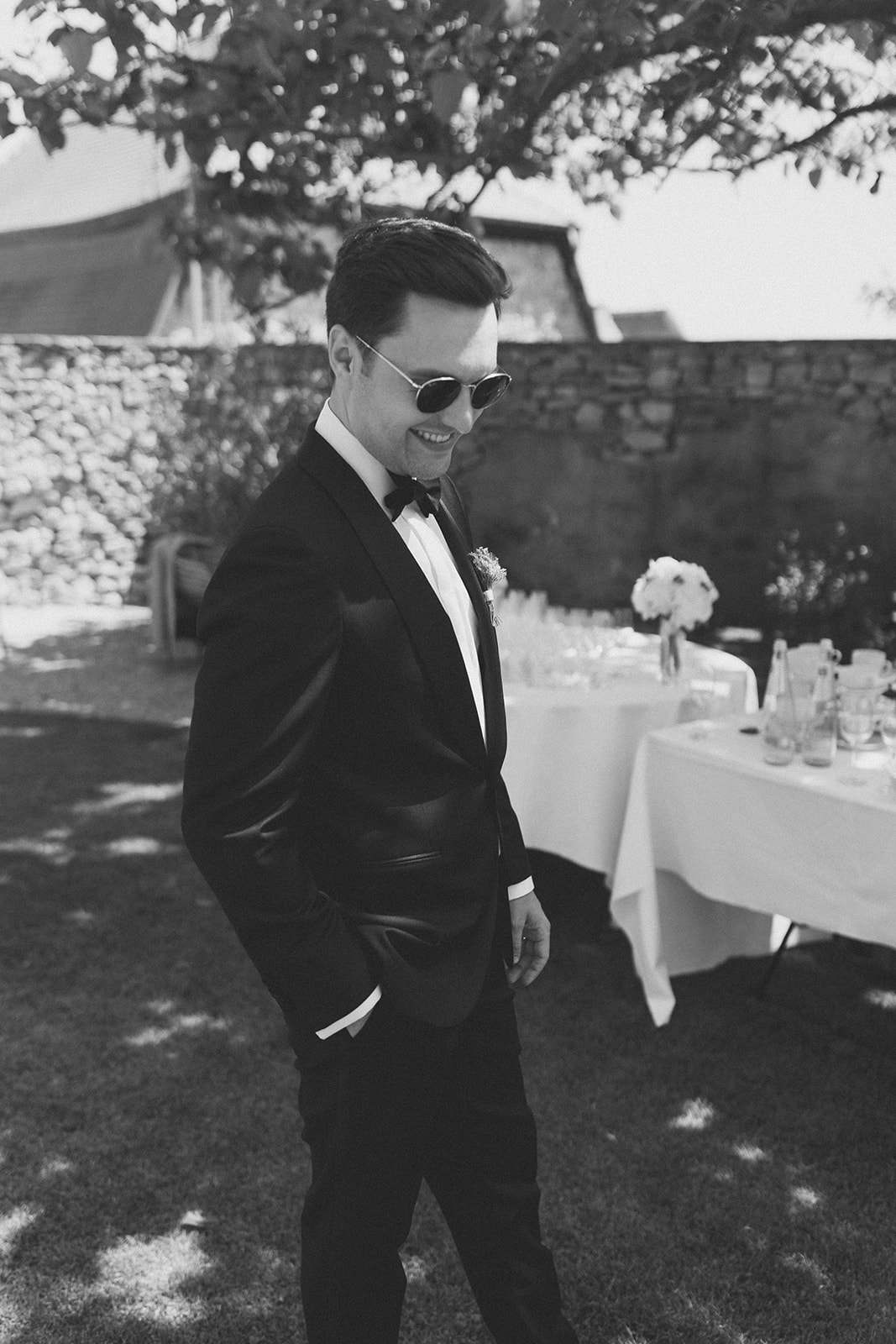 Eleganter Bräutigam mit Sonnenbrille steht auf Rasen