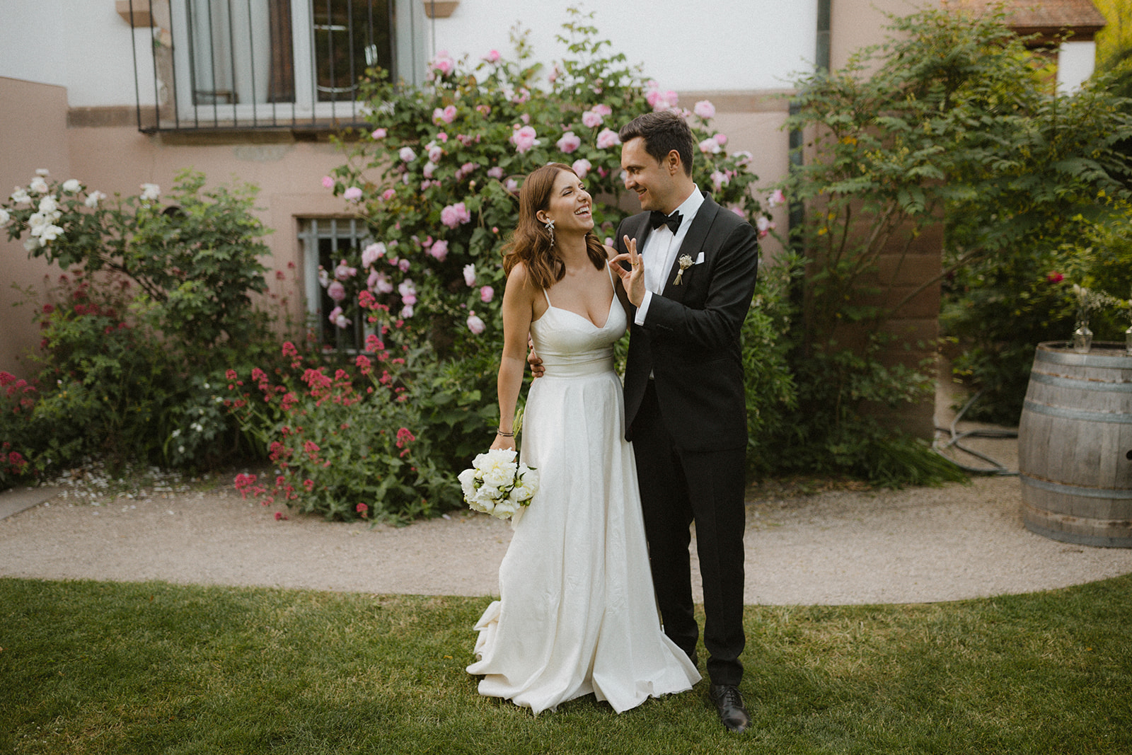 elegantes Brautpaar küsst sich im Rosengarten