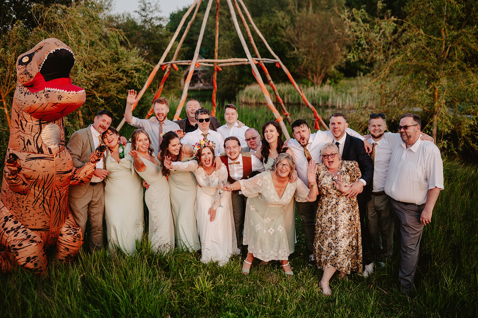 Golden hour group photo at the naked tipi at wilderness weddings in kent with an inflatable dinosaur!!