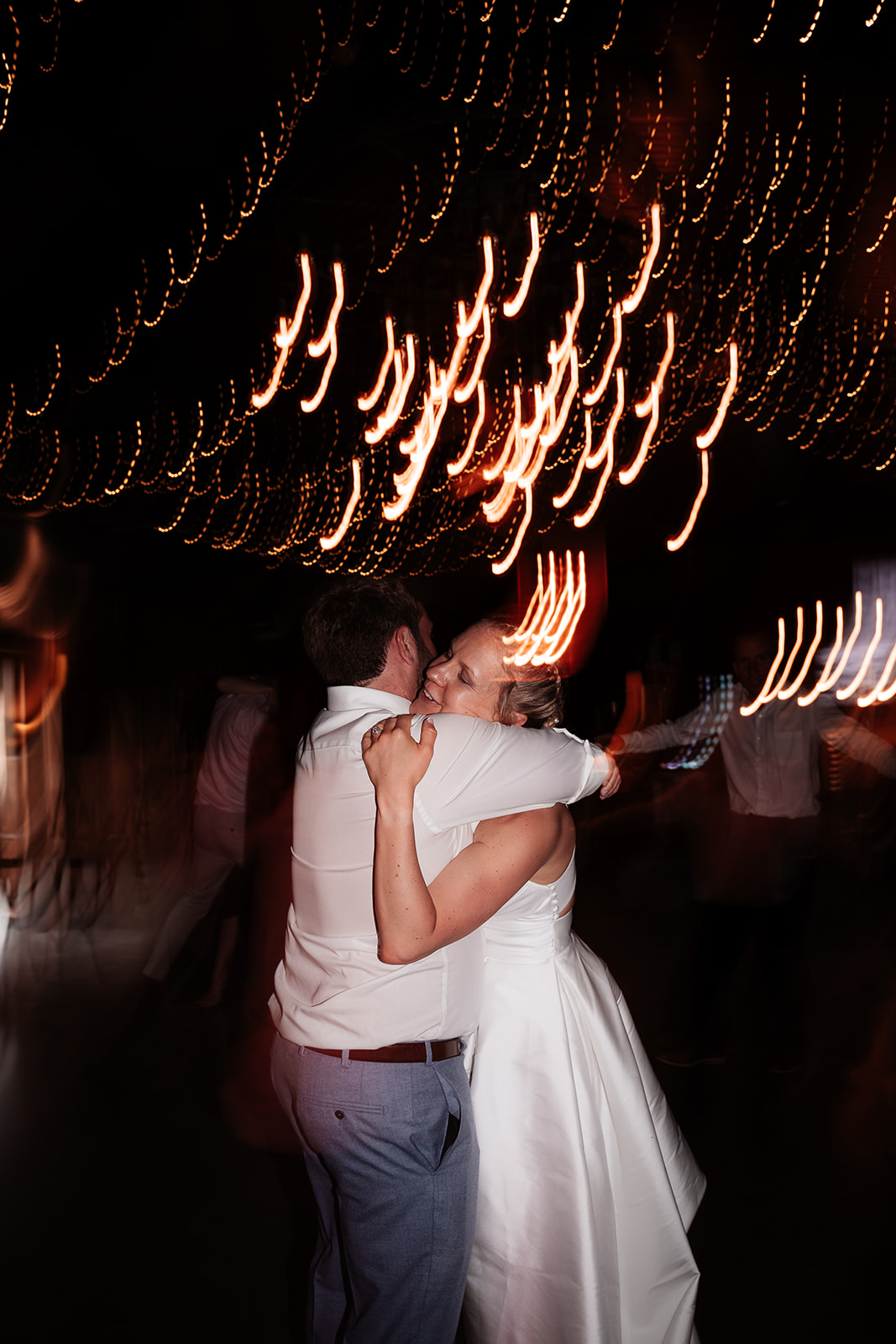 Bride and groom hug on the dancefloor surrounded by light trails at a summer wedding at Silchester Farm