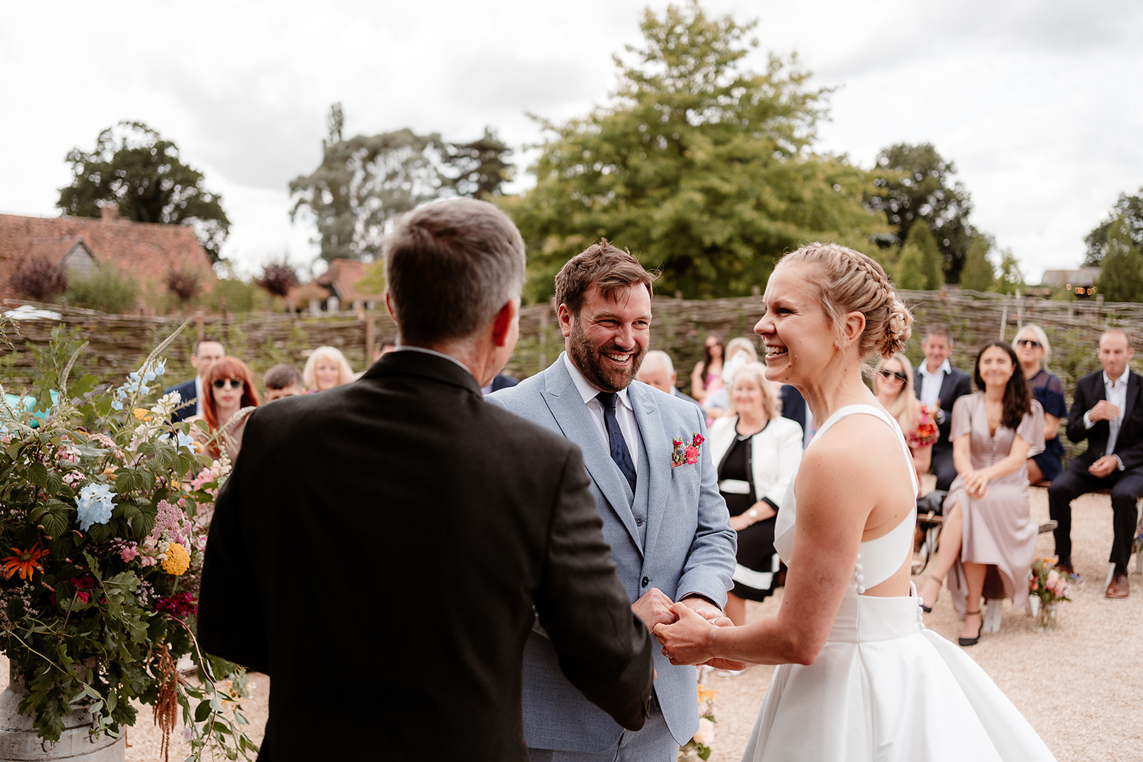Bride and groom laugh together during their outdoor ceremony at a summer wedding at Silchester Farm