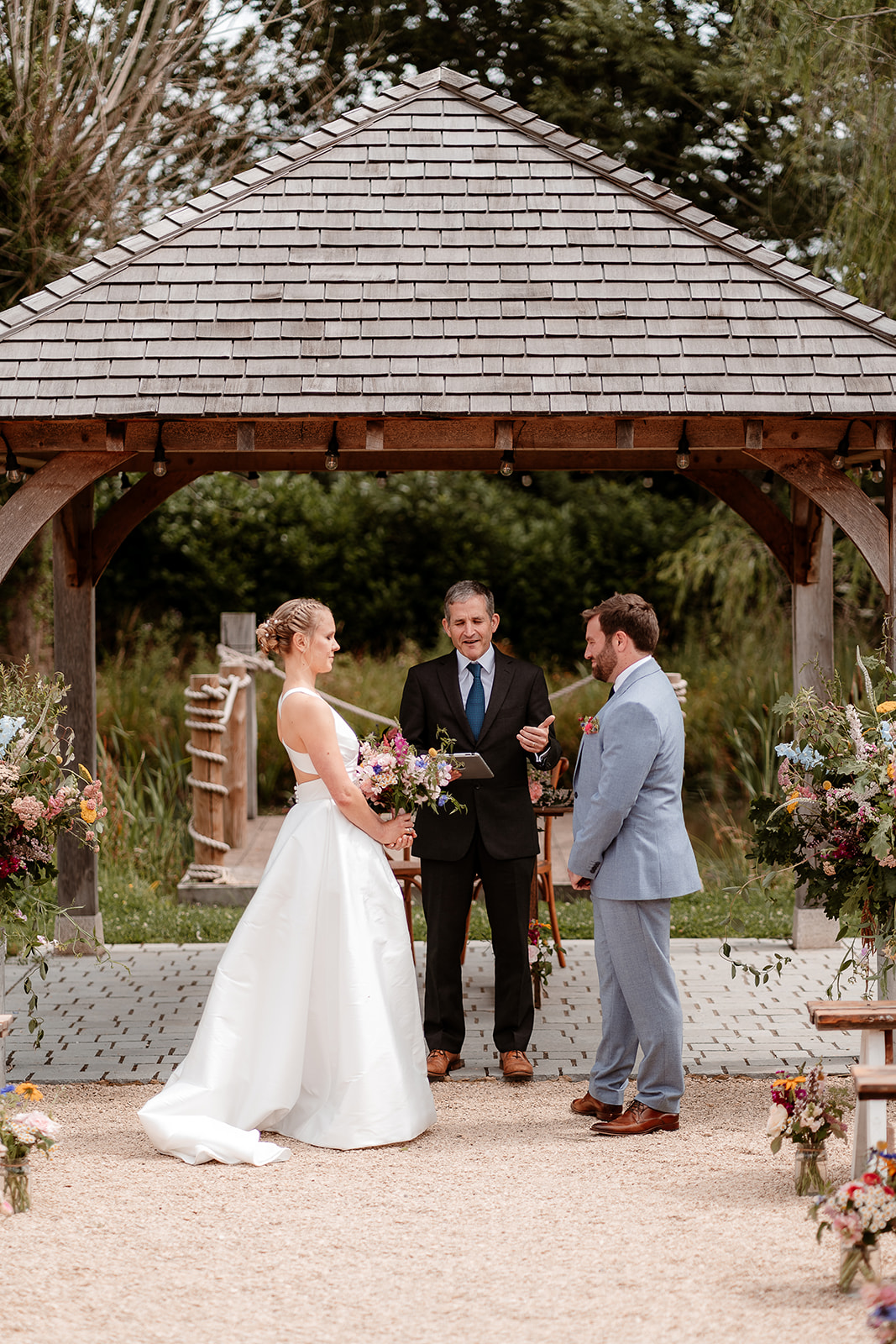 Bride and groom stand together at their outdoor ceremony at a summer wedding at Silchester Farm