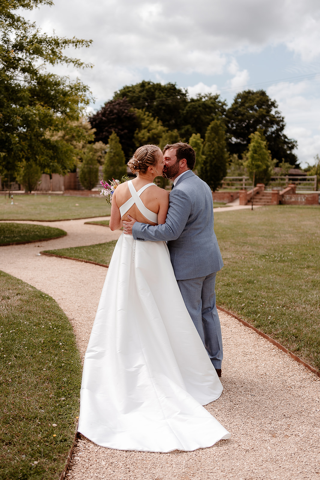Bride and groom stop to share a kiss after their outdoor wedding ceremony at Silchester Farm