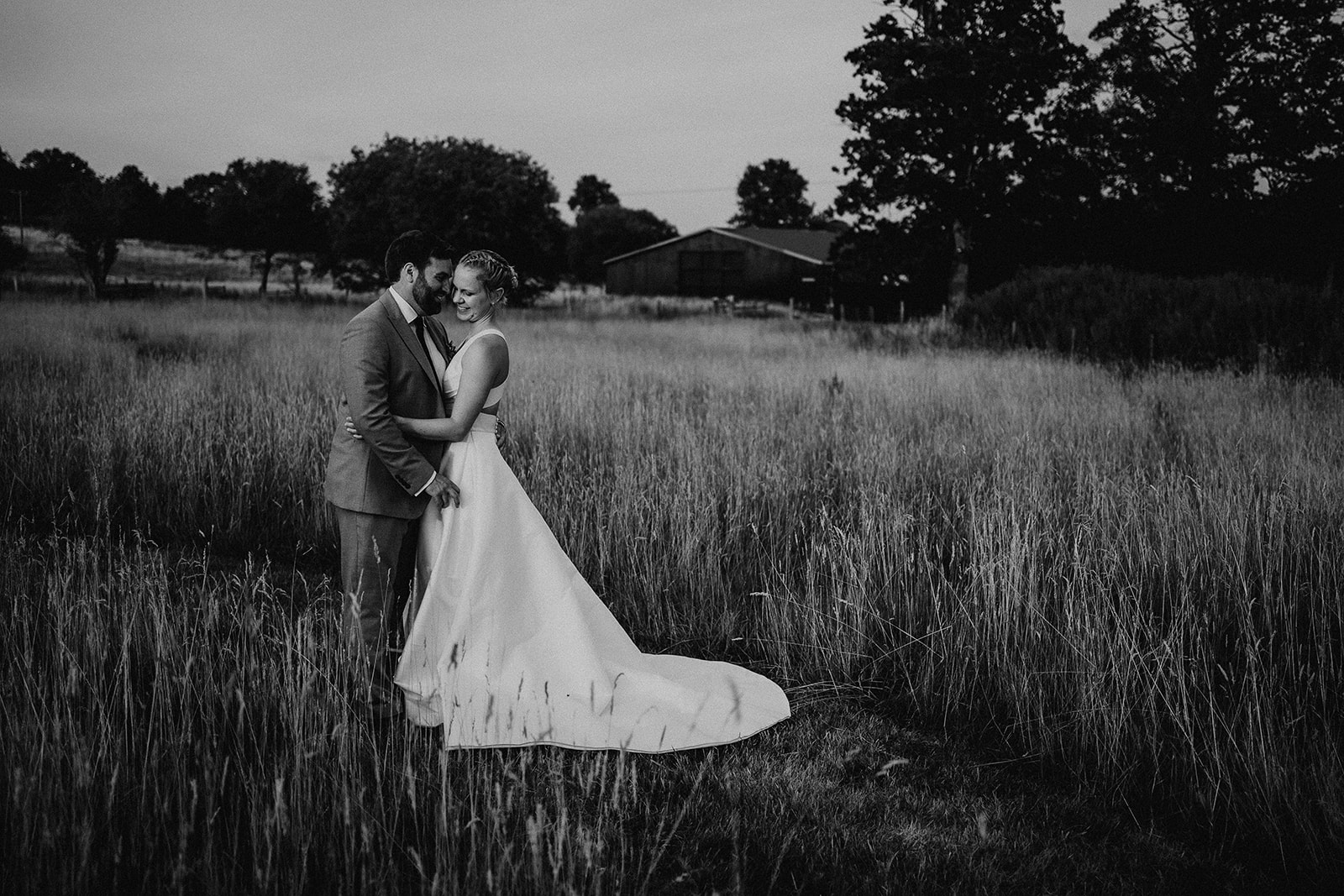 Bride and groom in the sunset with the farm behind them at a summer wedding at Silchester Farm