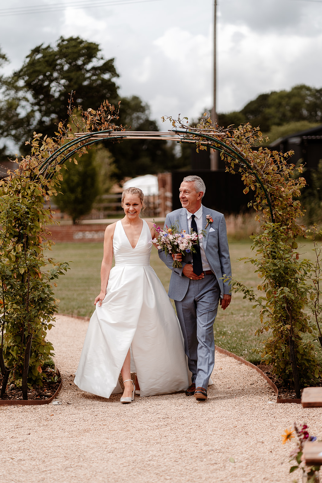 Bride and her father walk down the aisle at a summer wedding at Silchester Farm