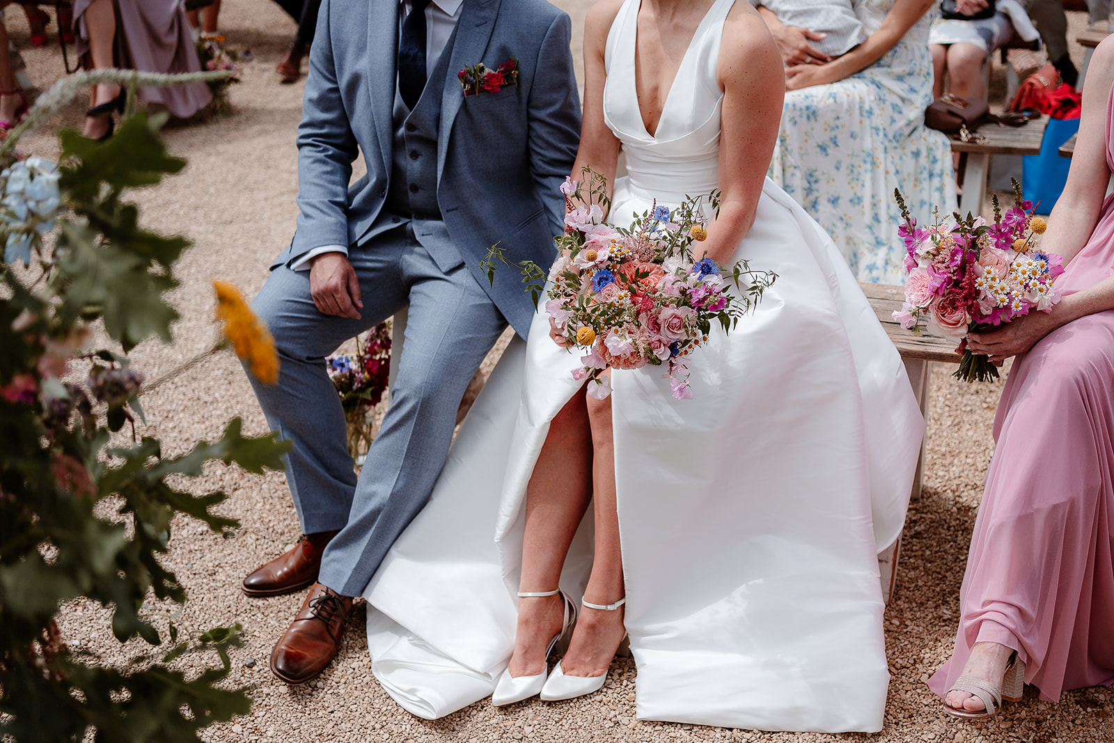 Close up of the bride sat holding her bouquet on her lap at a summer wedding at Silchester Farm