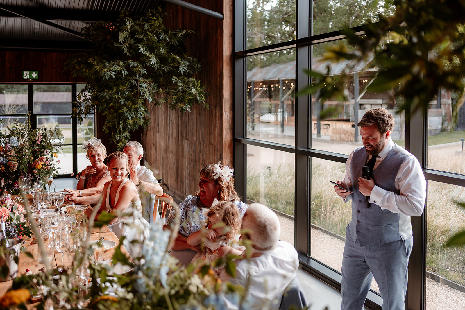 Groom gives his speech as the bride smiles up at him at a summer wedding at Silchester Farm