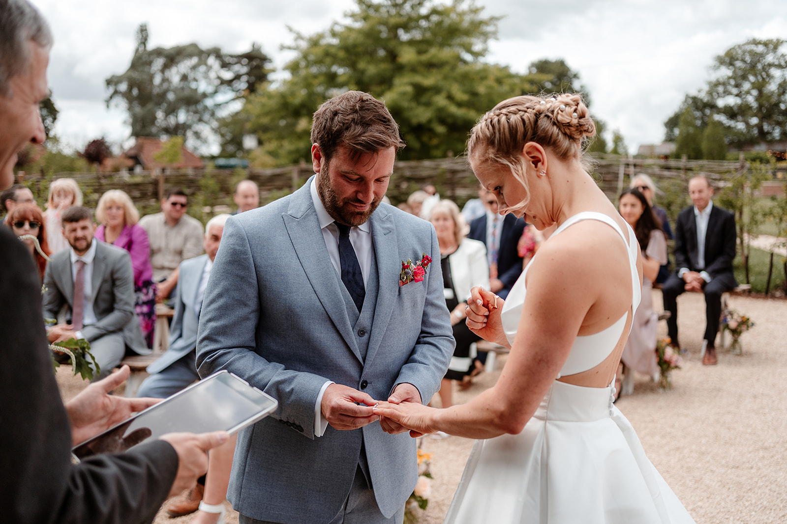 Groom puts the wedding ring on his bride at a summer wedding at Silchester Farm
