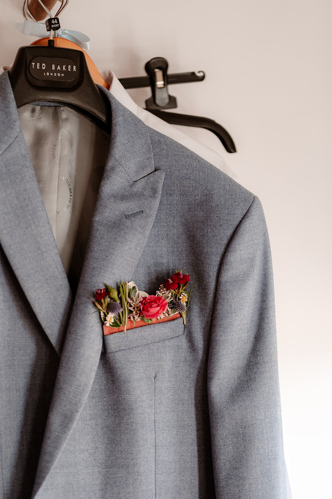 Groom's blue jacket with a pink floral pocket square at a summer wedding at Silchester Farm