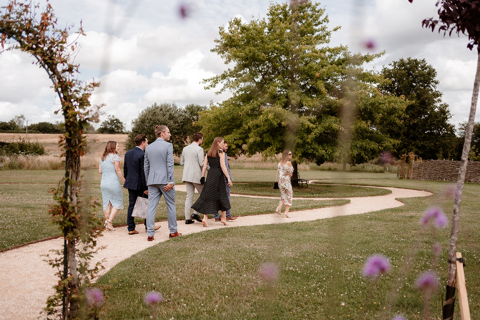 Guests walk to the outdoor ceremony space at a summer wedding at Silchester Farm