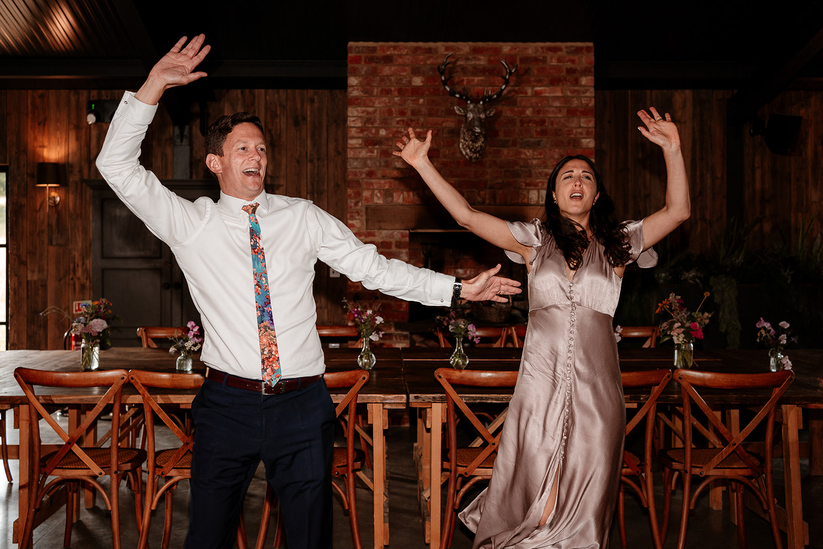 Two guests dance with their arms in the air at a summer wedding at Silchester Farm