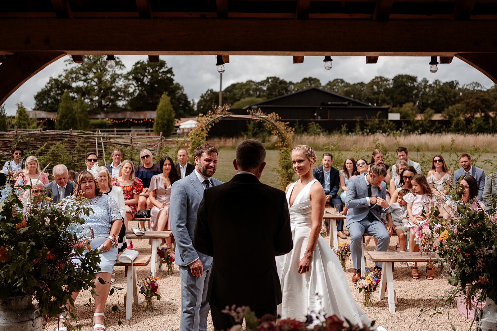 View of the outdoor wedding ceremony from behind the officiant looking at the couple and their guests at Silchester Farm