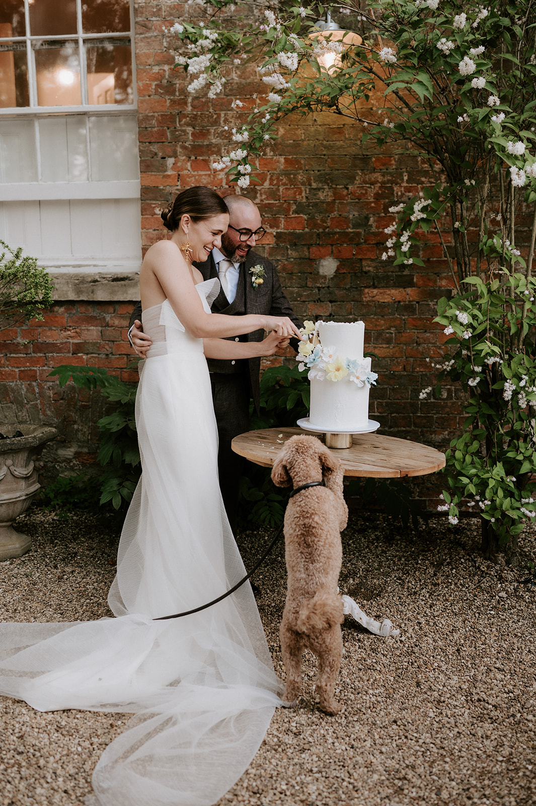 couple cutting cake with dog at aswarby rectory during reception