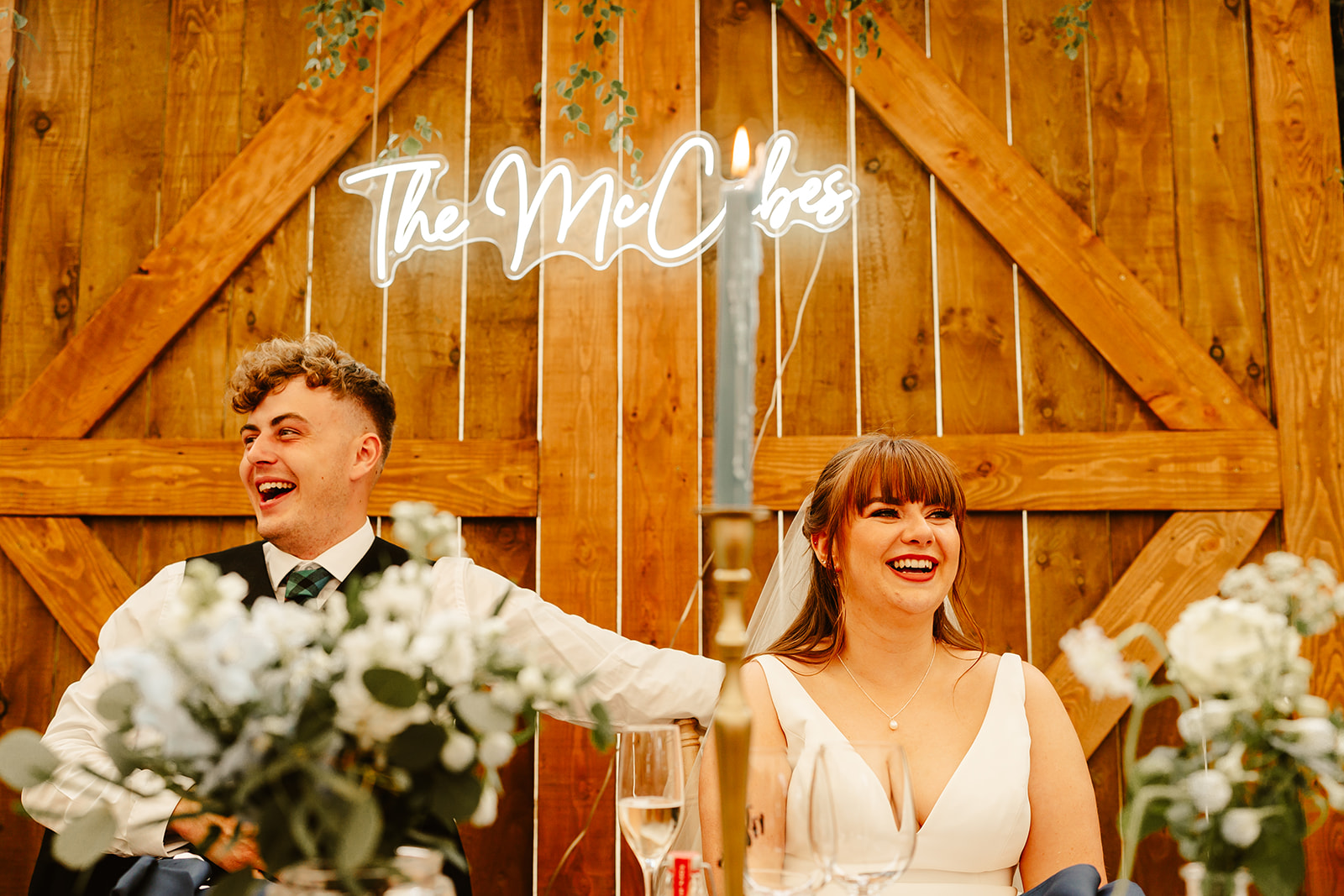 Couple laughing at a wedding speech at Elrick House Wedding Venue - there is a custom neon sign in the background