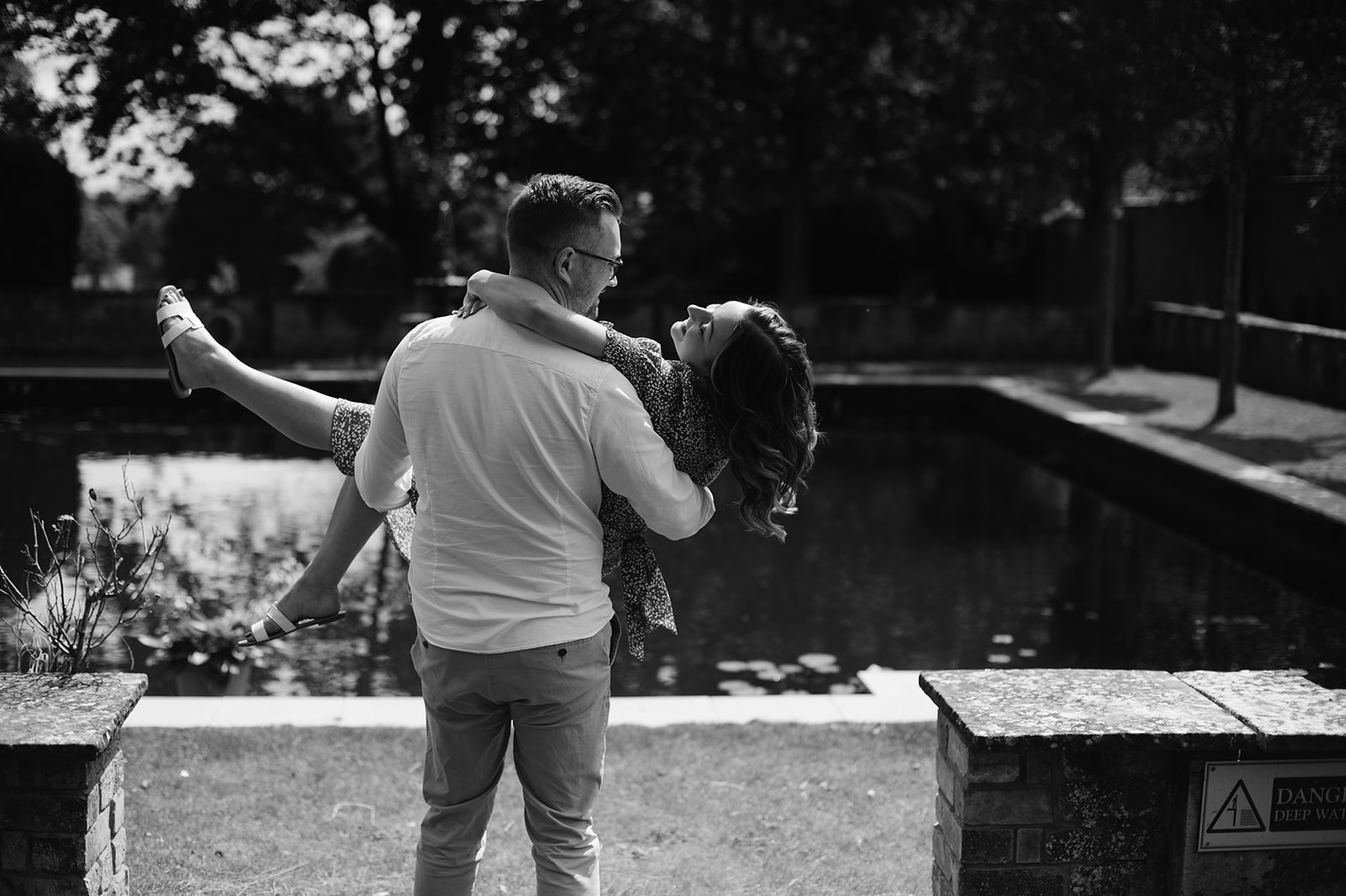 man lifting woman for romantic photos by the pond at Bourton Hall