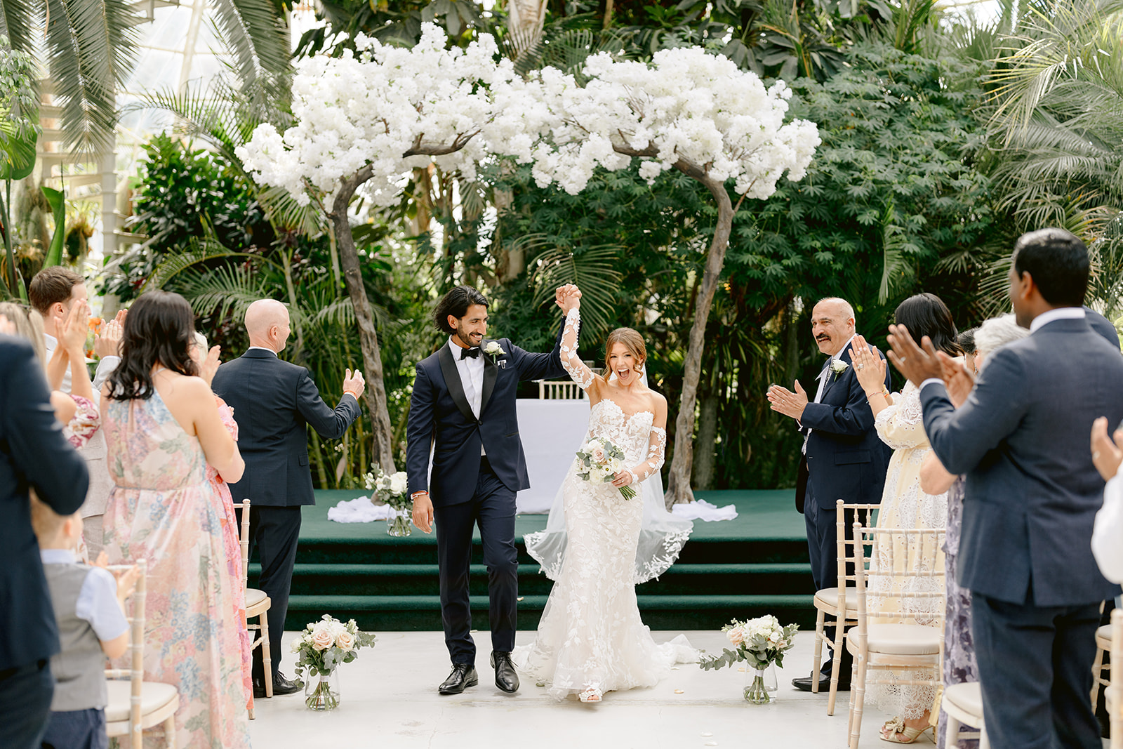 bride and groom with hands up celebrating them being just married at sefton park palm house wedding